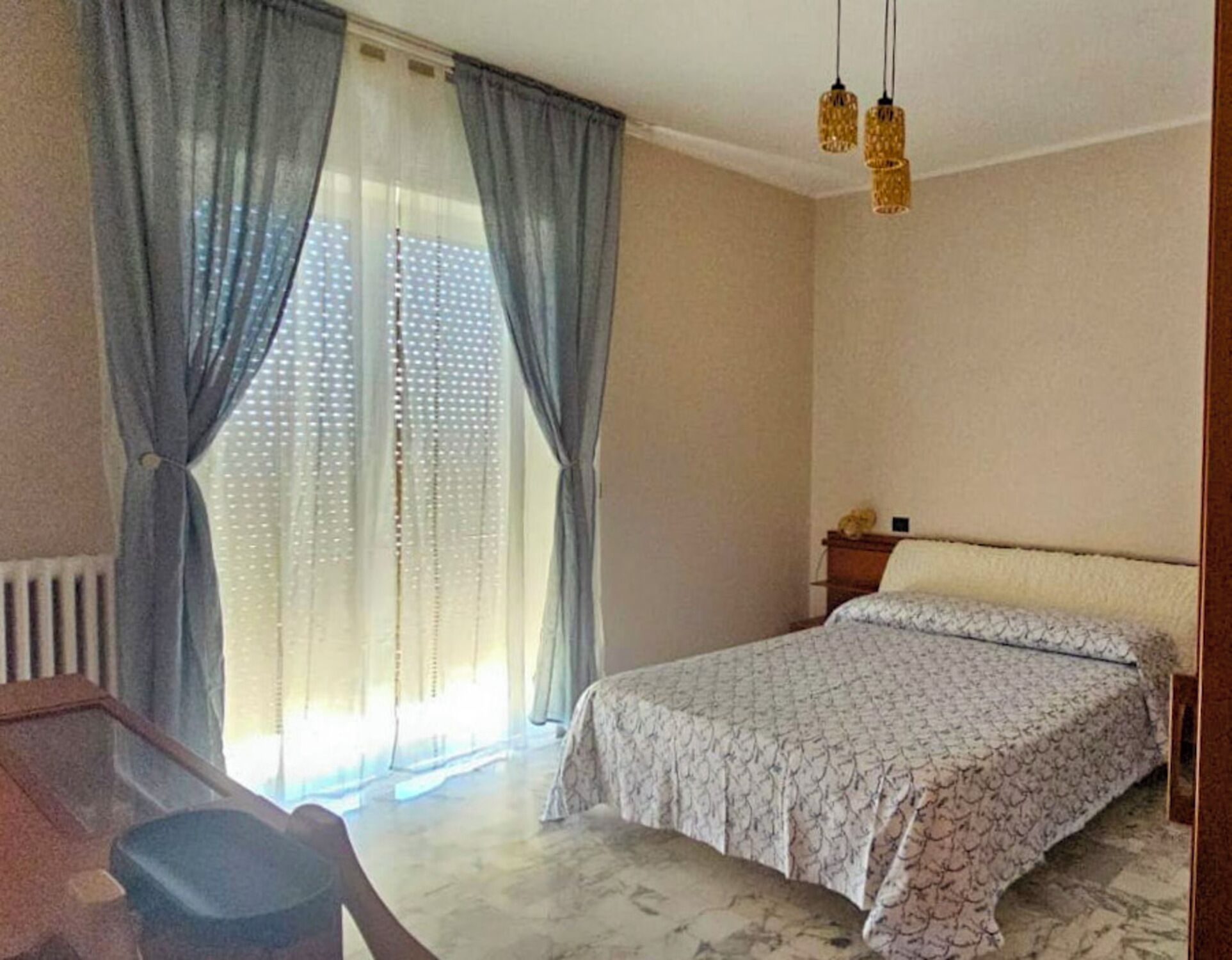Egy hálószoba, amelyben van egy ágy, függönyök, egy íróasztal és egy szék.