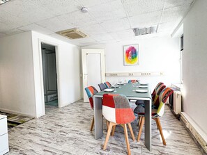 A dining area with a table set for six, surrounded by colorful chairs, a ceiling fan, and a painting on the wall. - Central Berlin Apartment for 8 with Parking (Berlin)
