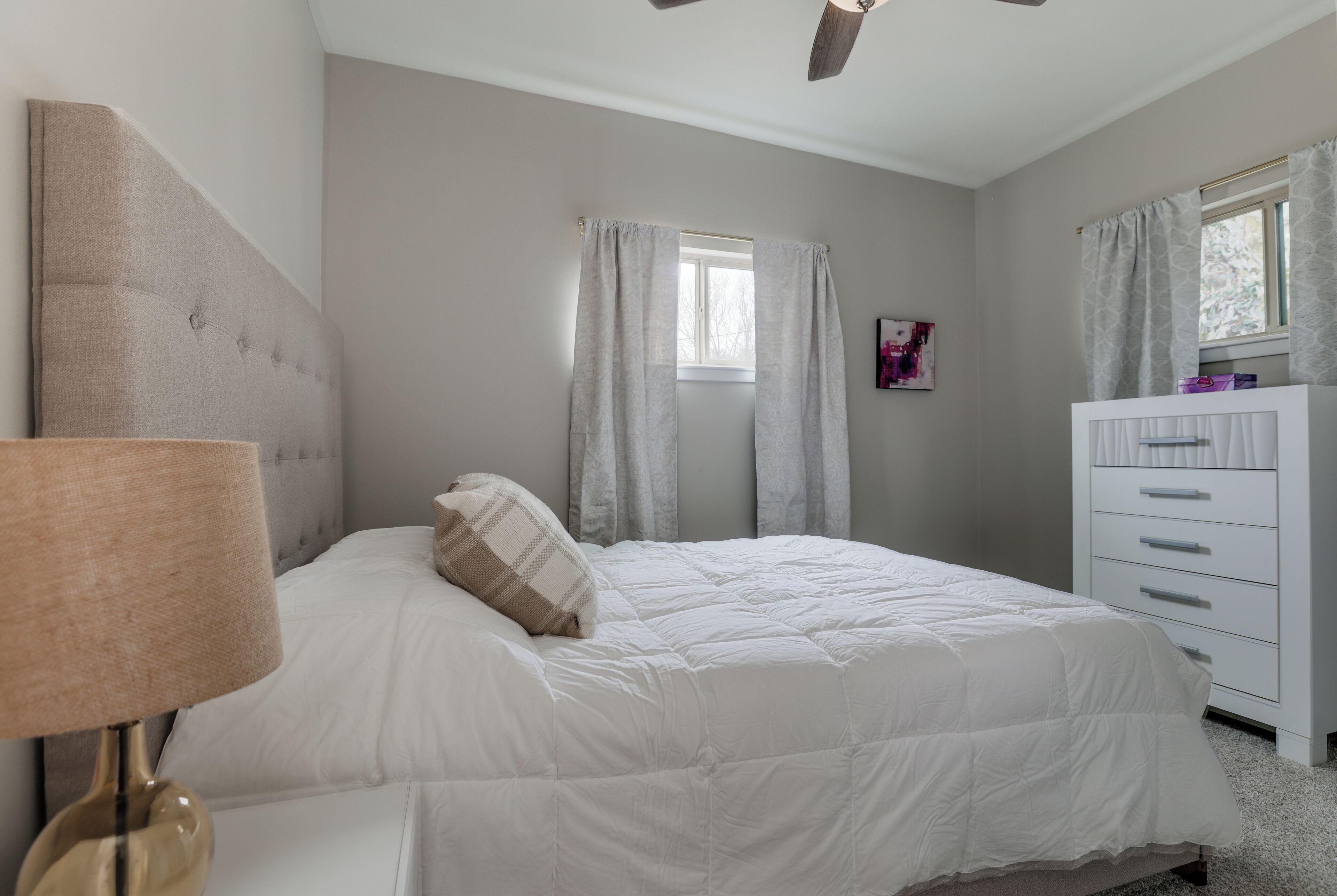 A bedroom with a bed, a nightstand, a dresser, and a ceiling fan.