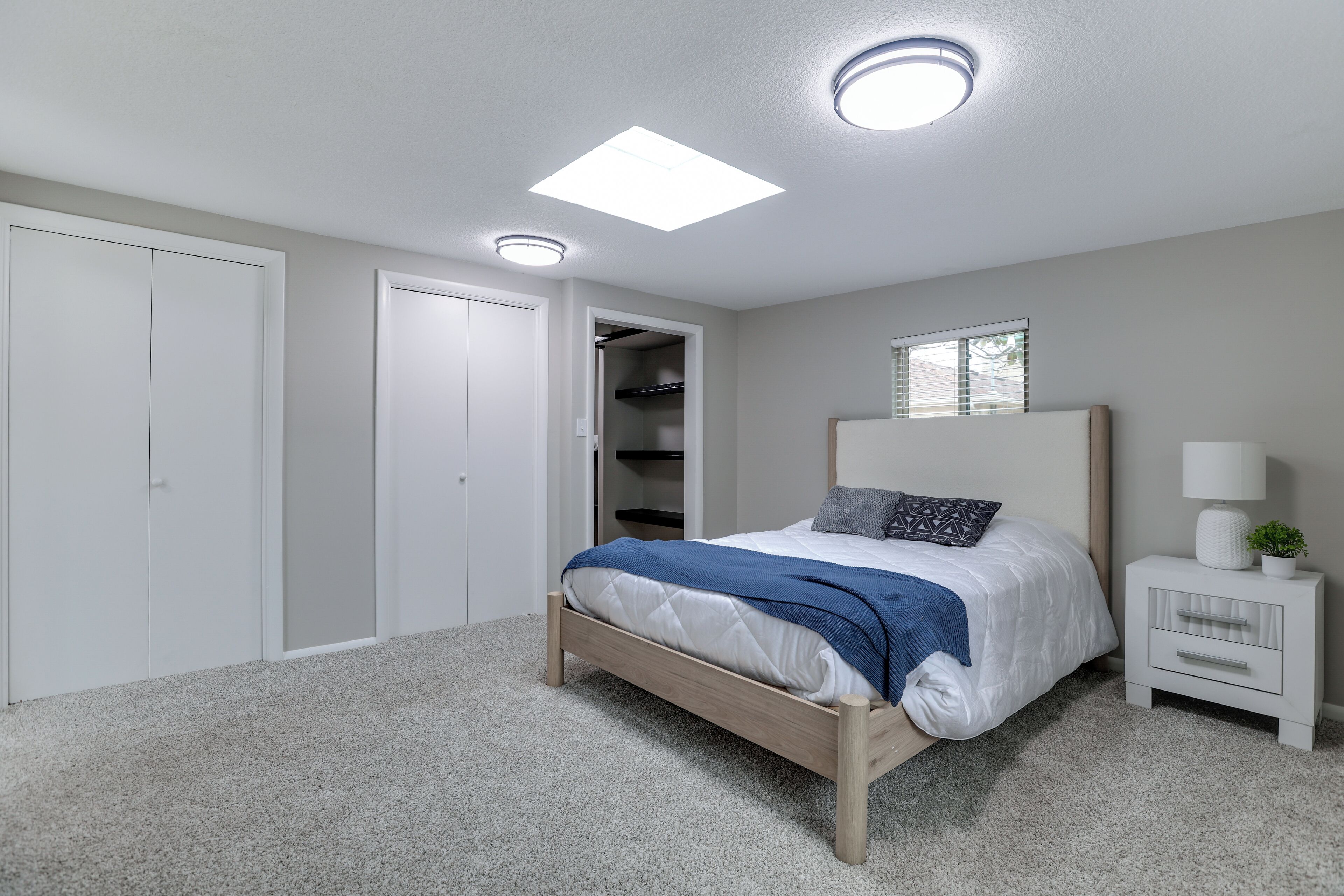 A bedroom with a bed, a nightstand, a closet, and a ceiling light.