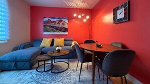 Uma sala de estar moderna com um sofá modular, uma mesa de centro redonda e uma mesa de jantar com cadeiras.