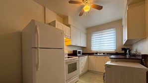 Uma cozinha compacta com geladeira, micro-ondas, forno e máquina de lavar roupa.