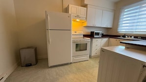 Uma cozinha compacta com eletrodomésticos brancos, micro-ondas e armários.