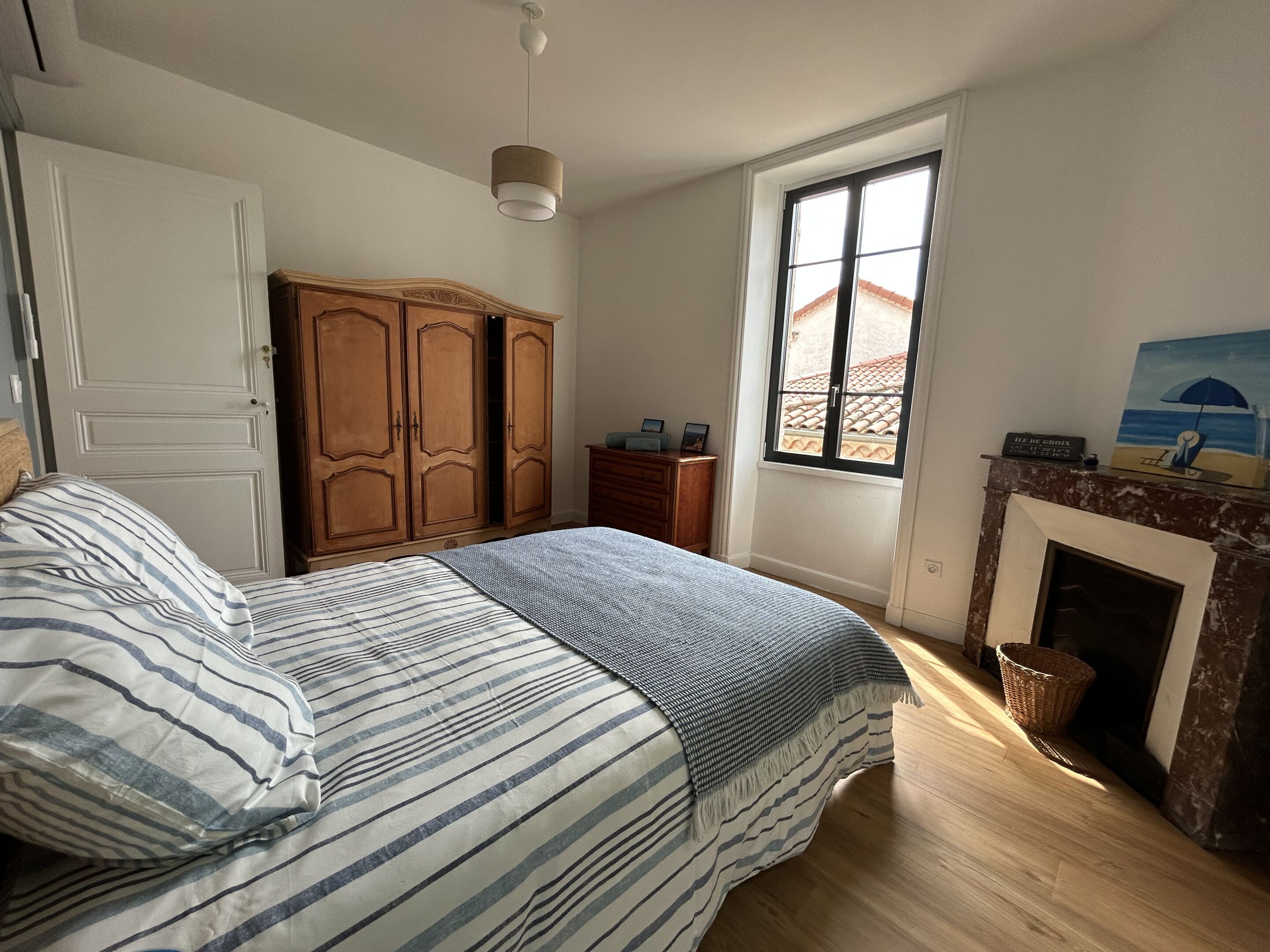 Une chambre à coucher avec un lit, une armoire, une fenêtre et une cheminée.