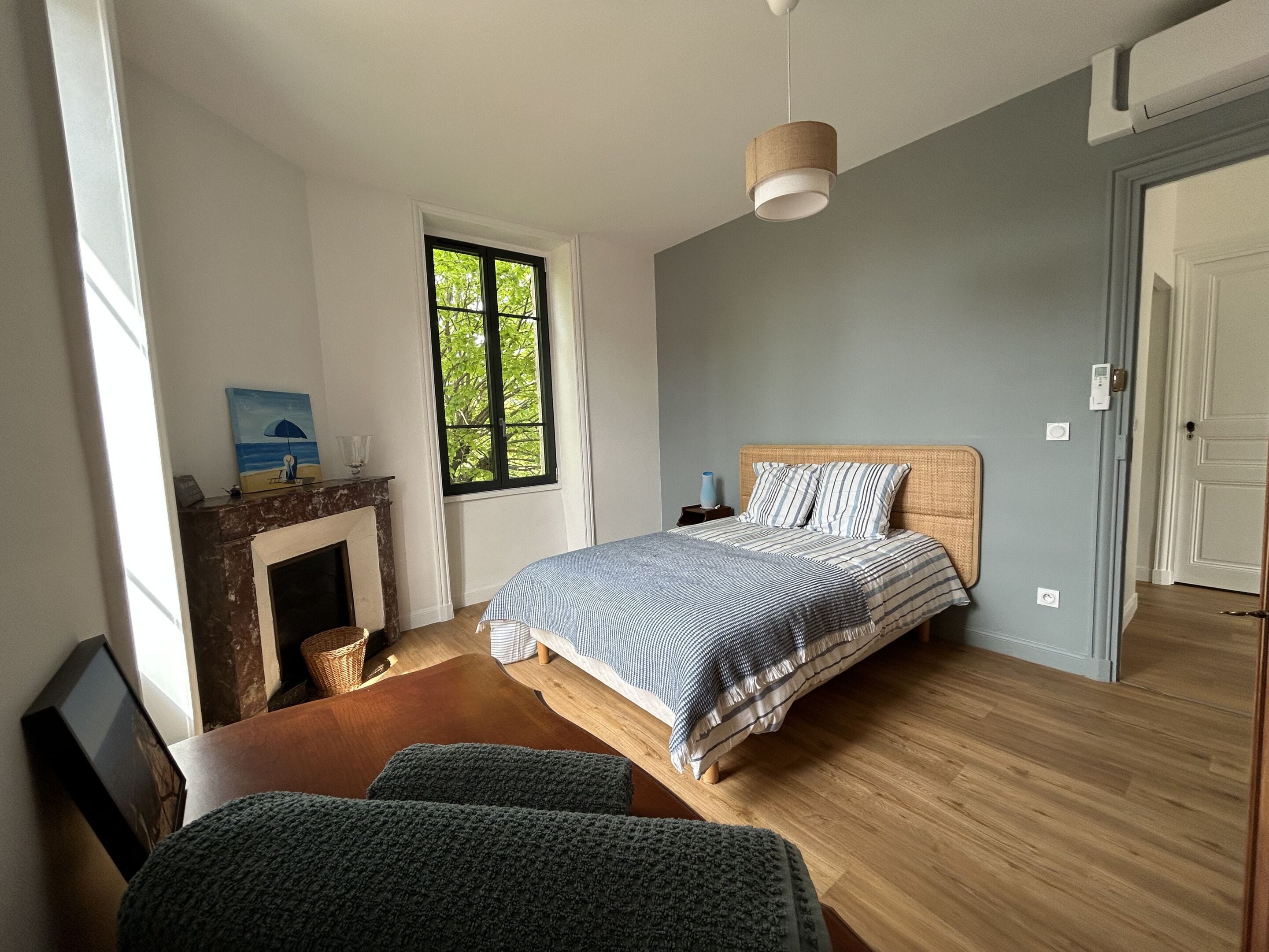A bedroom with a bed, a window, a fireplace, and a door.