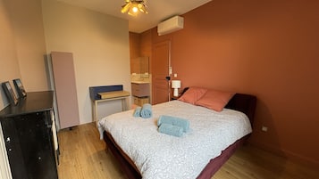 Un dormitorio con cama, mesita de noche, cómoda, espejo y lámpara colgante.