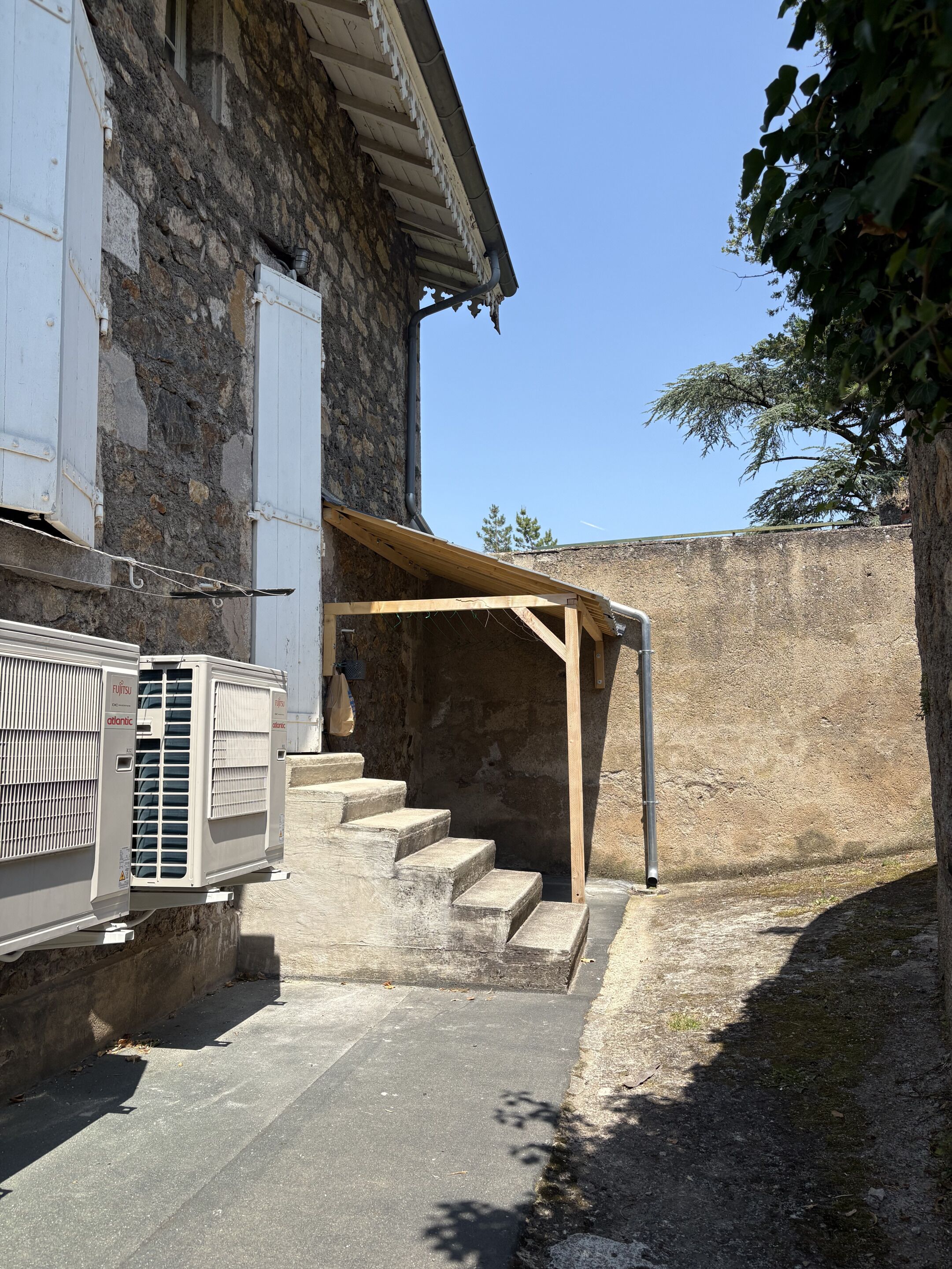 Un edificio de piedra con una escalera de madera que conduce a un espacio cubierto.