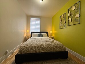 Une chambre à coucher avec un lit, des lampes de chevet, une fenêtre et un mur vert.