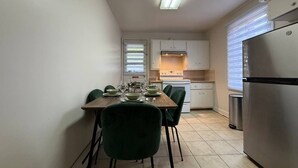 Eine kleine Küche mit einem Esstisch für vier Personen, einem Kühlschrank und einem Herd.