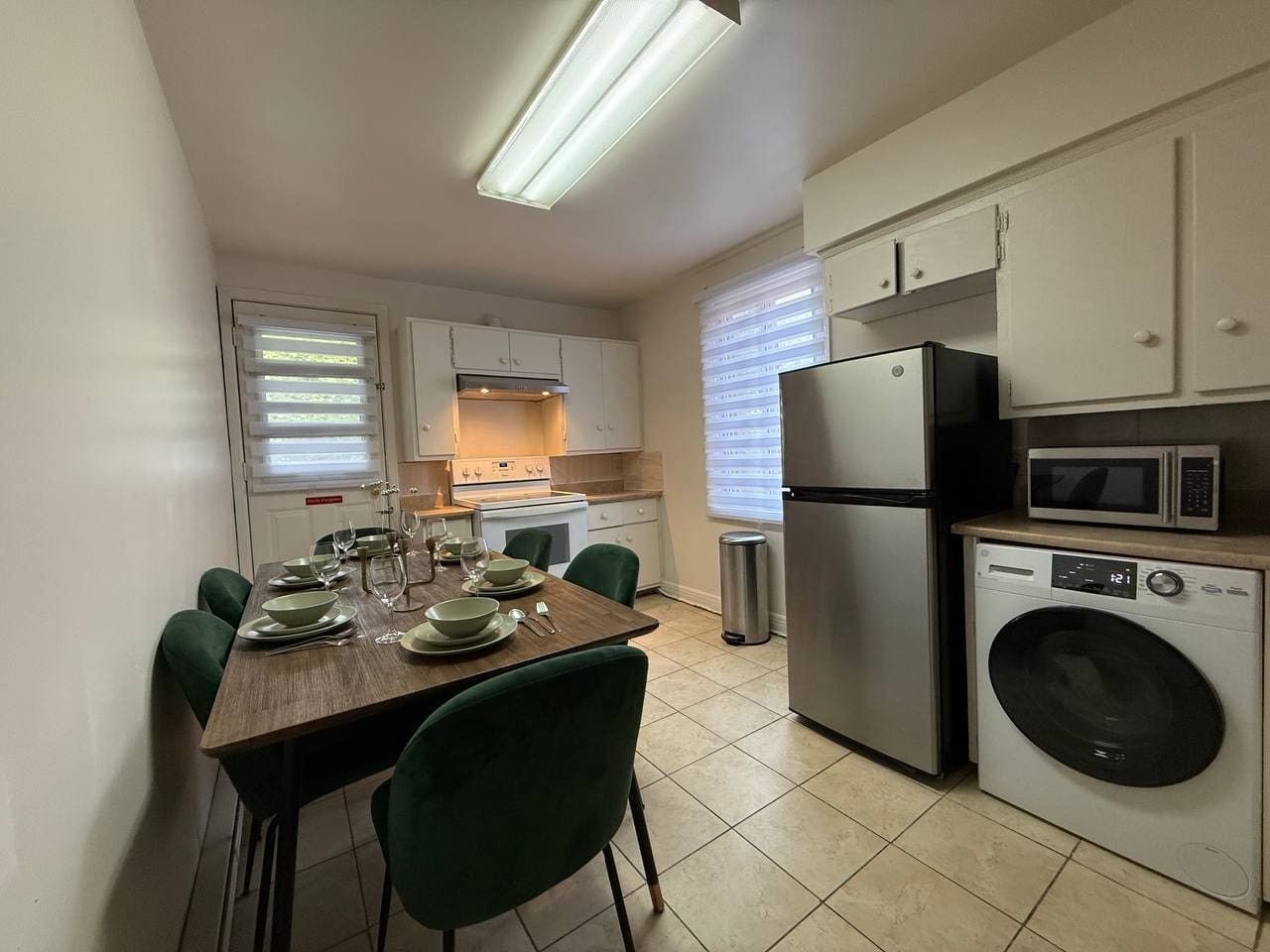 Cocina compacta con comedor, equipada con microondas, refrigerador y lavadora.