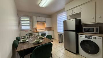 Cocina compacta con comedor, equipada con microondas, refrigerador y lavadora.