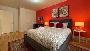 Ein Schlafzimmer mit einem Bett, einem Nachttisch, einer Lampe und einer Tür.