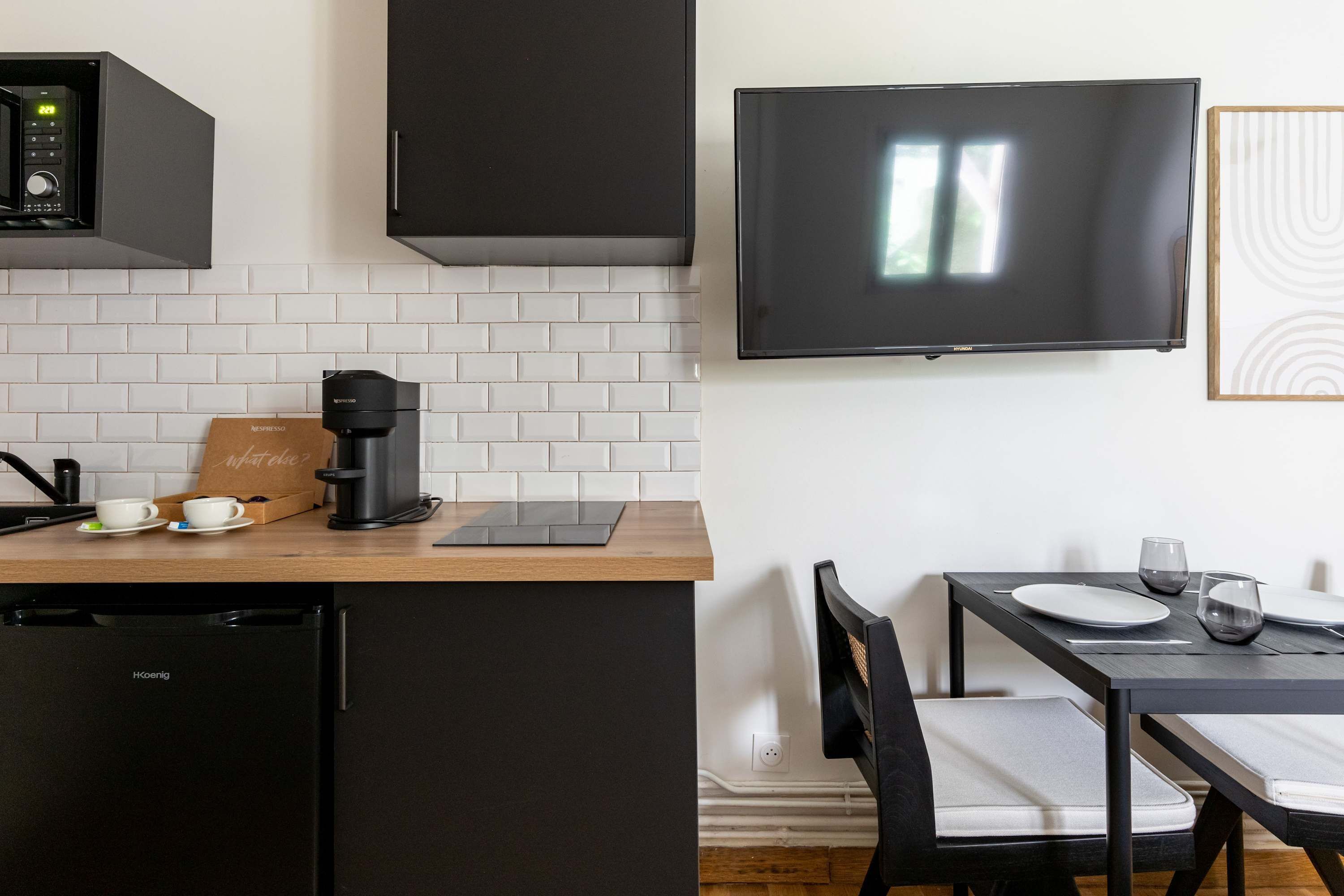 Une cuisine moderne équipée d’une machine à expresso intégrée, d’une cafetière et d’une tablette posée sur le plan de travail.
