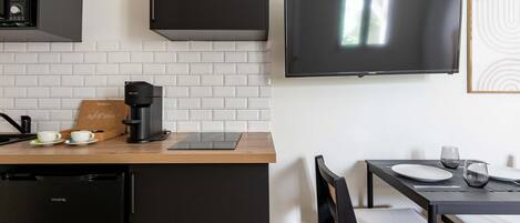 Une cuisine moderne équipée d’une machine à expresso intégrée, d’une cafetière et d’une tablette posée sur le plan de travail.