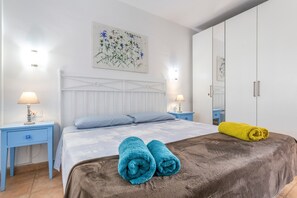 Un dormitorio con cama, dos mesitas de noche, un armario y un cuadro en la pared.
