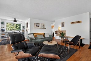 A modern living room with a sofa, chairs, a coffee table, and a dining area with a bench.