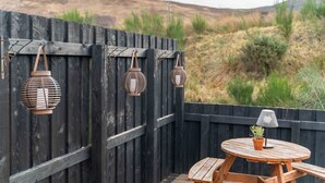 A wooden deck with a round table and benches, surrounded by a wooden fence. - Apex Studio Pod & Jacuzzi Bath (Fort William)