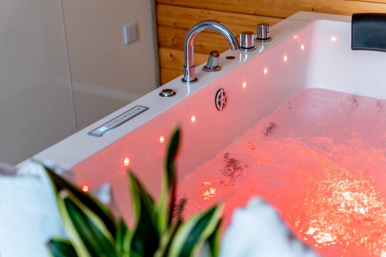 A modern bathtub with a built-in heater, multiple control knobs, and LED lights.