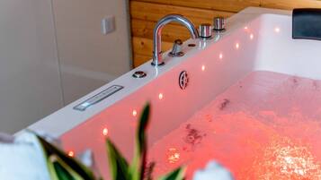 A modern bathtub with a built-in heater, multiple control knobs, and LED lights.