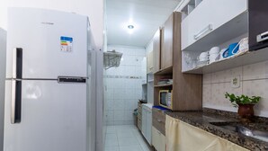 Uma cozinha com geladeira branca, armários de madeira, micro-ondas e pia.