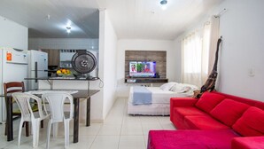 Um espaço compacto com cozinha compacta, área de refeições, TV, sofá vermelho e cama.