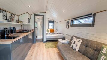 A compact, modern cabin with a kitchenette, a cozy sleeping area, and a window providing natural light.