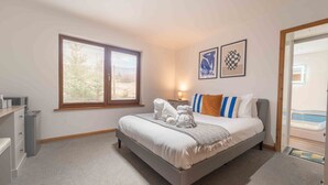 A bedroom with a bed, a bedside table, a lamp, and a window. - Ben View Room & Jacuzzi Bath (Fort William)