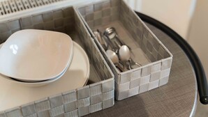 A kitchen area with a white countertop, a sink, and two grey storage baskets containing kitchen utensils. - Ben View Room 2 in Fort William (Fort William)