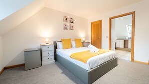 A bedroom with a bed, bedside tables, a wardrobe, and a bathroom visible through an open door. - Ben View Room 2 in Fort William (Fort William)