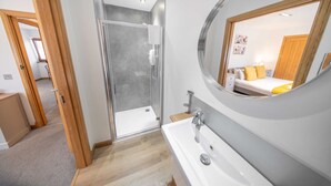 A modern bathroom with a glass shower enclosure, a large mirror, and a white sink. - Ben View Room 3 in Fort William (Fort William)