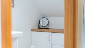 A small bathroom with a white sink, a mirror on a wooden shelf, and a white cabinet. - Ben View Room 3 in Fort William (Fort William)