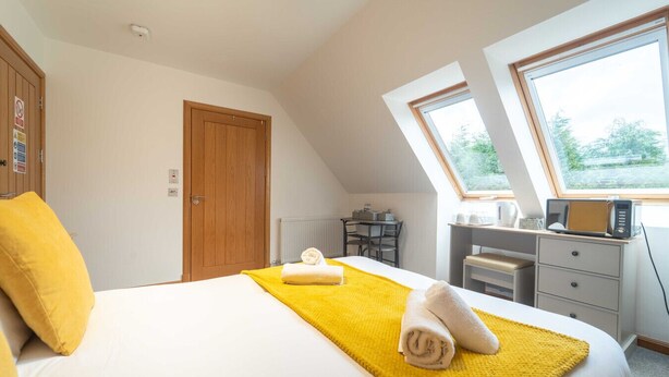 A bedroom with a bed, a desk, a chair, and a window. - Ben View Room 3 in Fort William (Fort William)