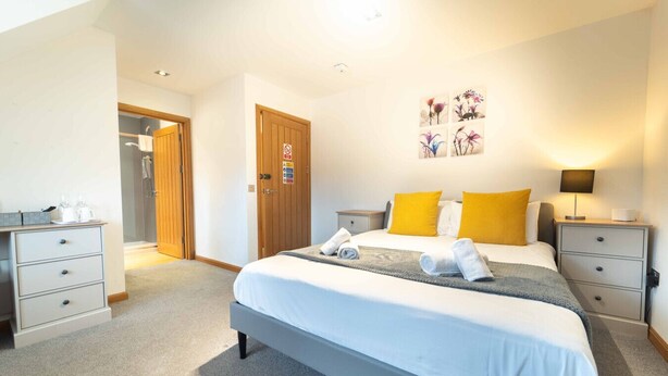 A hotel room with a large bed, two bedside tables, a desk, and a shower area. - Ben View Room 4 in Fort William (Fort William)