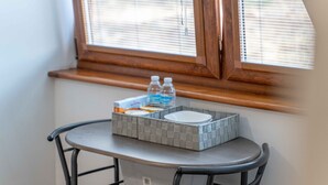A small table with a gray woven tray holding a box of tissues, a bottle of water, and a white container. - Ben View Room 4 in Fort William (Fort William)