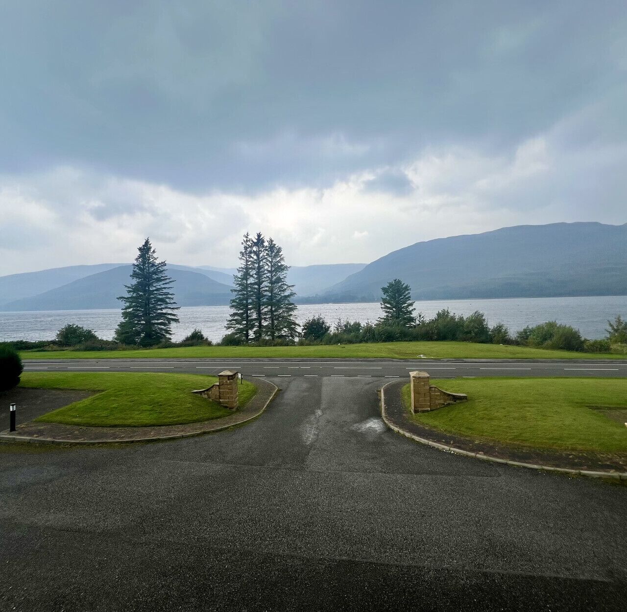 A road leading to a body of water with mountains in the background.