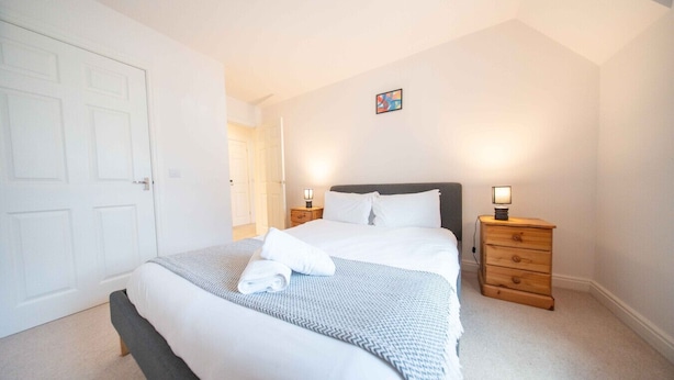 A neatly arranged bedroom with a bed, two bedside tables, and a door.