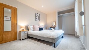 Een slaapkamer met een bed, nachtkastjes, een garderobe en een grote spiegel.