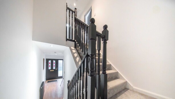 Una escalera moderna con barandillas negras y un rellano alfombrado.