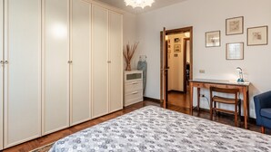 Een slaapkamer met een bed, kledingkast, bureau, stoel en een hanglamp.