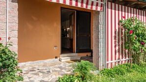 Een gebouw met een entree van stenen tegels, een rood-wit gestreepte luifel en een bakstenen muur.