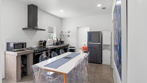 A compact kitchen with a microwave, stove, and refrigerator. There is a dining table with chairs and a window above it. - The Art House in Marfa (Marfa)