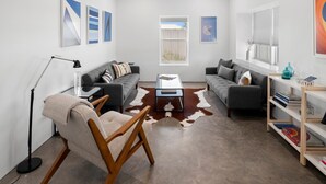 A modern living room with two sofas, a coffee table, a floor lamp, and a bookshelf. - The Art House in Marfa (Marfa)