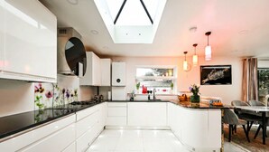 A modern kitchen with white cabinetry, a black countertop, and a skylight.