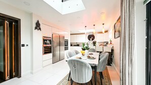 A modern kitchen with a skylight, a dining area with a table and chairs, and a view of the adjacent living space.