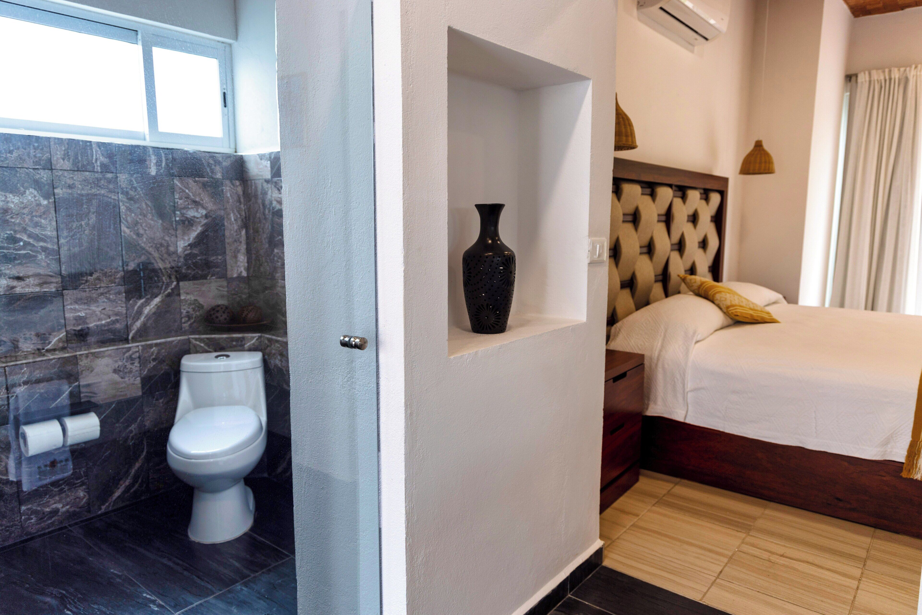 Casa de banho com sanita, azulejos de mármore e lavatório branco.