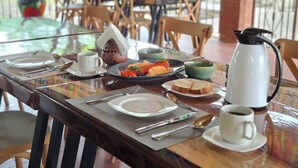 Ein Esstisch gedeckt mit Tellern, Besteck, einer Kaffeekanne und einem dekorativen, hausförmigen Gegenstand.