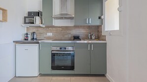 Een kleine keuken met een inbouwoven, magnetron en een kleine koelkast.