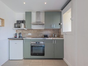 A compact kitchen with a built-in oven, microwave, and a small refrigerator. - Studio avec balcon et parking proche plages (Cannes)