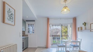 Een moderne keuken met een raam, een eethoek met tafel en stoelen, en een woonkamer met een bank.
