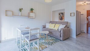 Een moderne woonkamer met een bank, twee stoelen, een eettafel en een kamerkleed met een patroon.